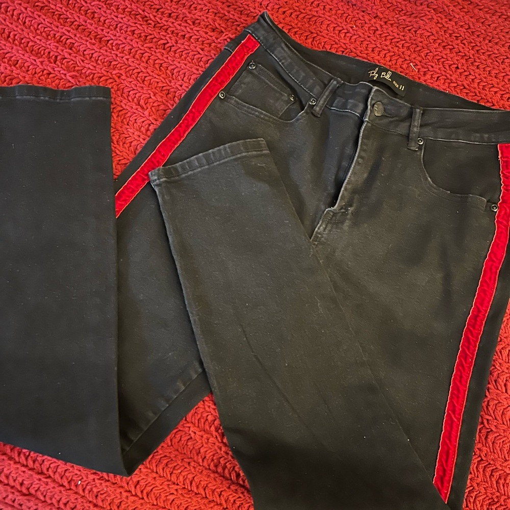 Black jean pants wit red velvet stripe.